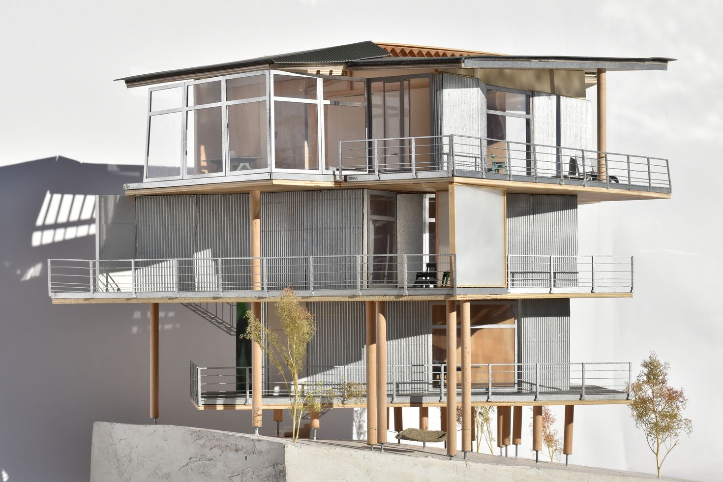 Architectural model of a modern residential design featuring prefabricated timber construction, showcasing a sustainable wooden structure with multiple balconies and large windows, illustrating contemporary modular building aesthetics.