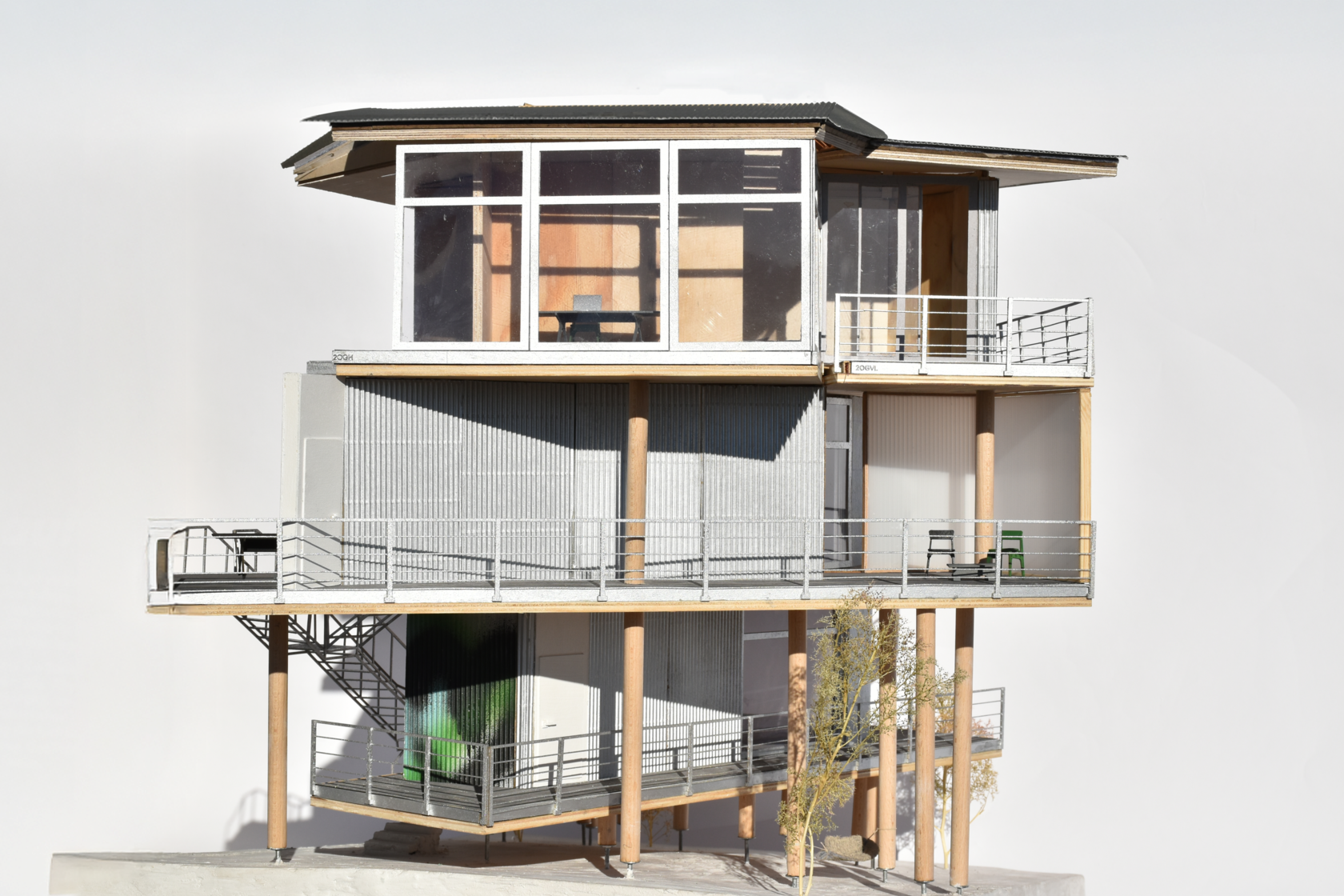 Architectural scale model of a modern residential building, highlighting timber construction, corrugated cladding, and various balconies, providing a detailed view of the building materials and design.