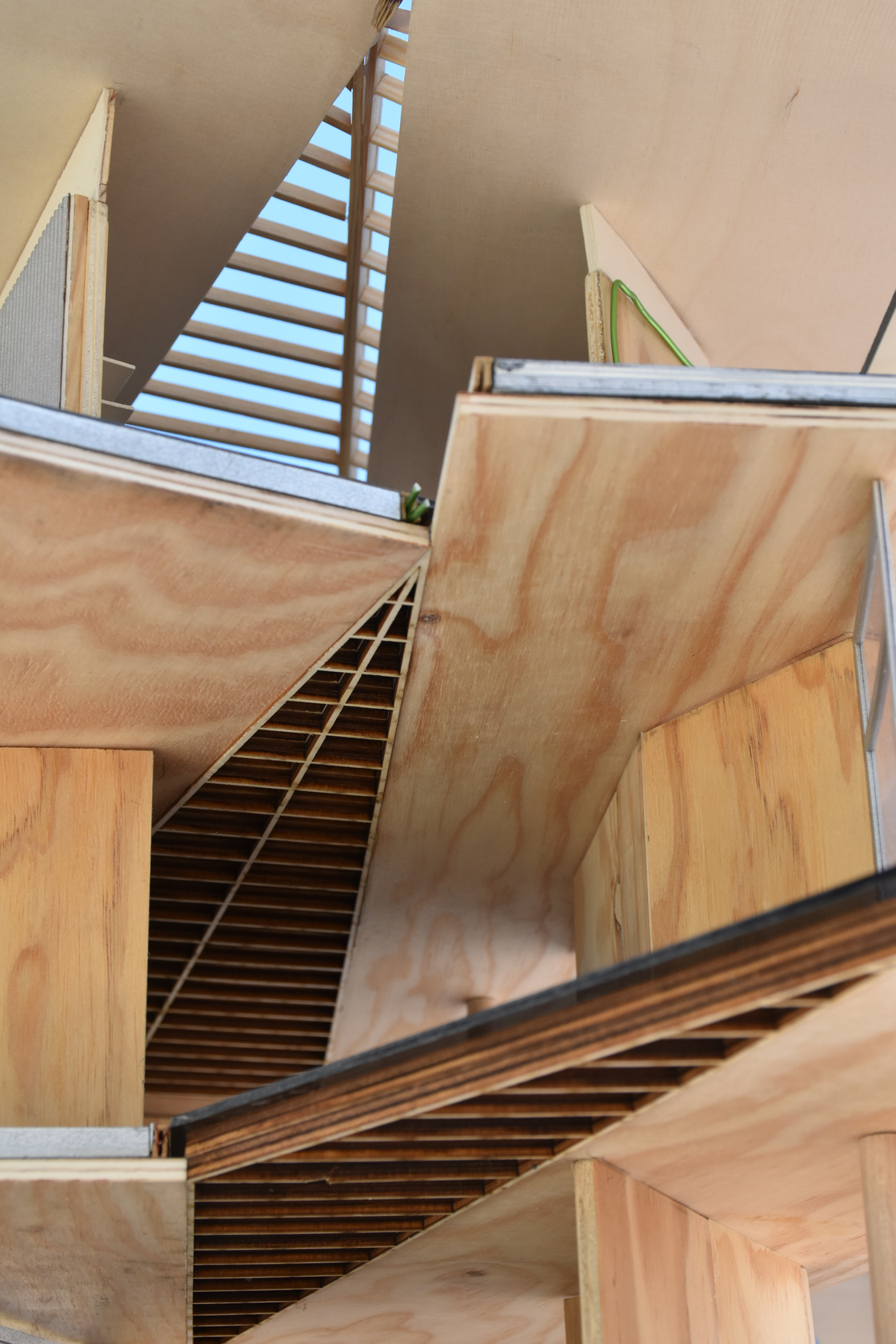 Detailed interior view of an architectural scale model, showcasing a wooden staircase within a timber construction, highlighting the intricate wood structure and interior design elements.