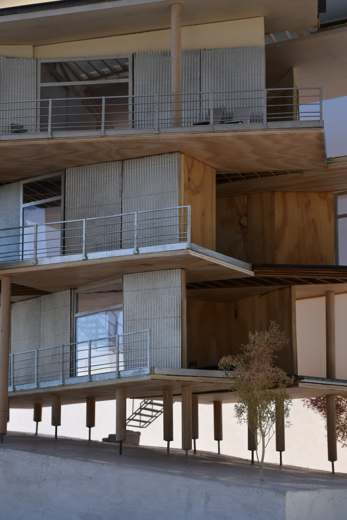 Detailed architectural scale model of a prefabricated wood residential building, featuring timber construction, corrugated cladding, balconies, and emphasizing specific construction details.