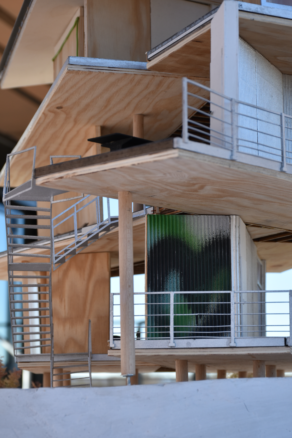 Interior architectural scale model of a modern residential building, showcasing a wooden staircase, balconies with railings, and detailed timber construction, offering insight into the interior spaces.