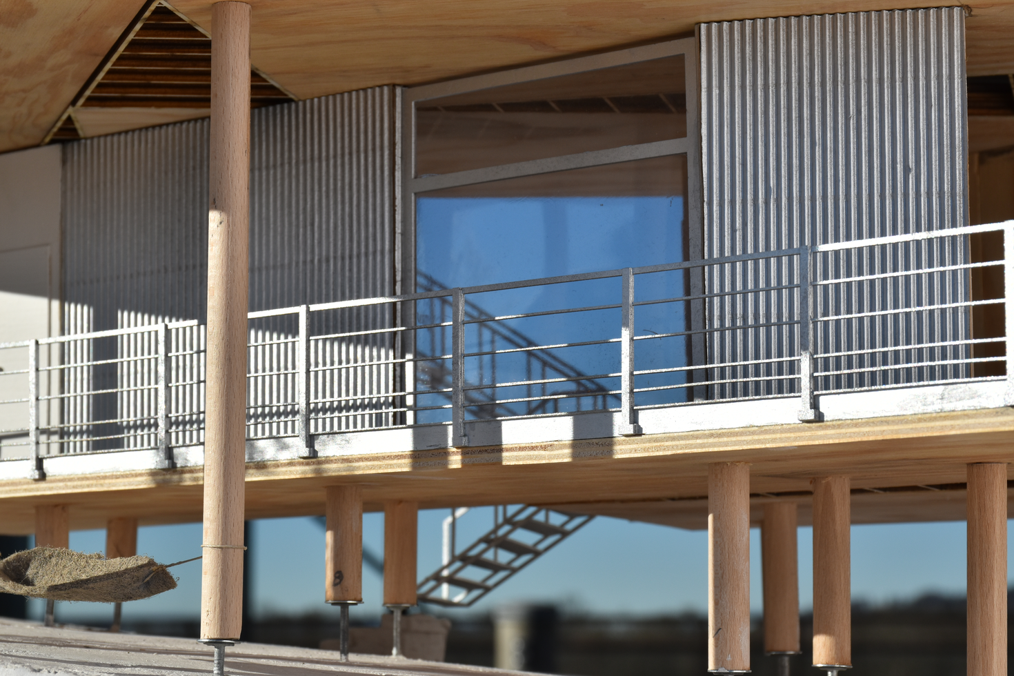 Architectural scale model of a modern residential house on stilts, featuring wood and metal cladding, showcasing a contemporary design with elevated living spaces.